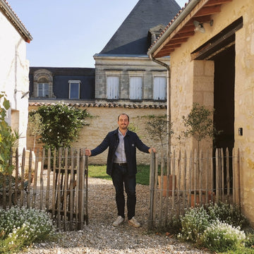 Guillaume Bougès souriant et appuyé sur les piquets de la clôture devant le gîte