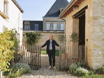 Guillaume Bougès souriant et appuyé sur les piquets de la clôture devant le gîte